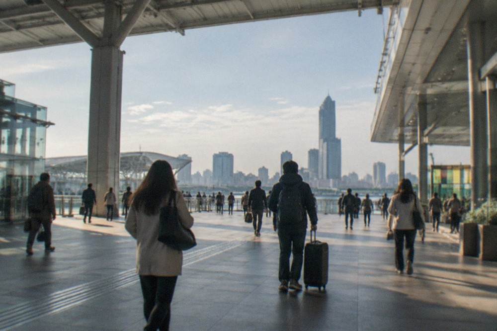 Passengers walking through a modern railway station concourse with departure boards overhead