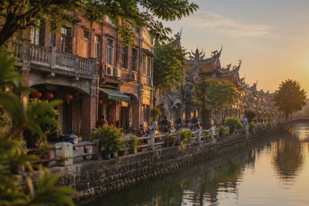 Historic brick buildings along a canal in Tainan at golden hour