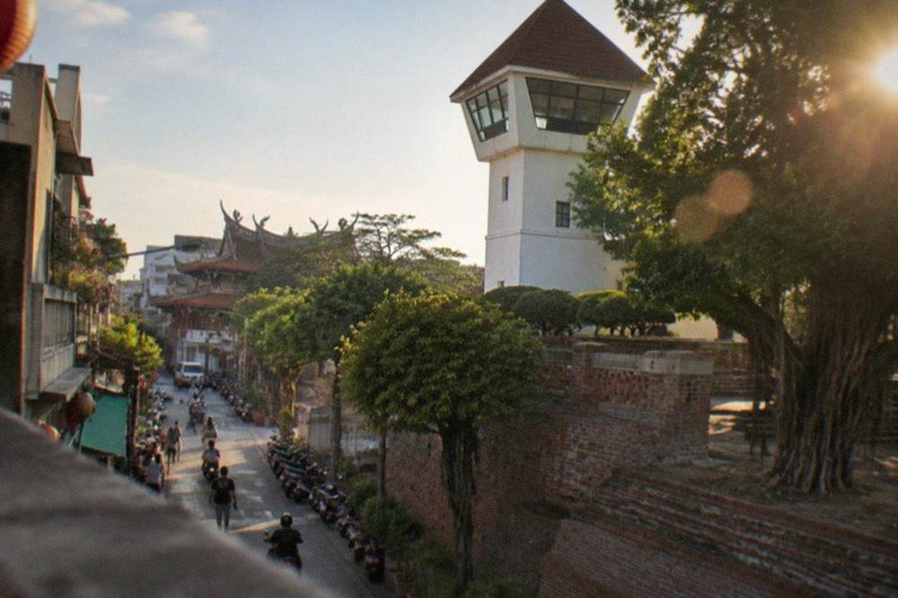 A white-walled lookout tower with a pointed roof rising above brick foundations at Anping Old Fort