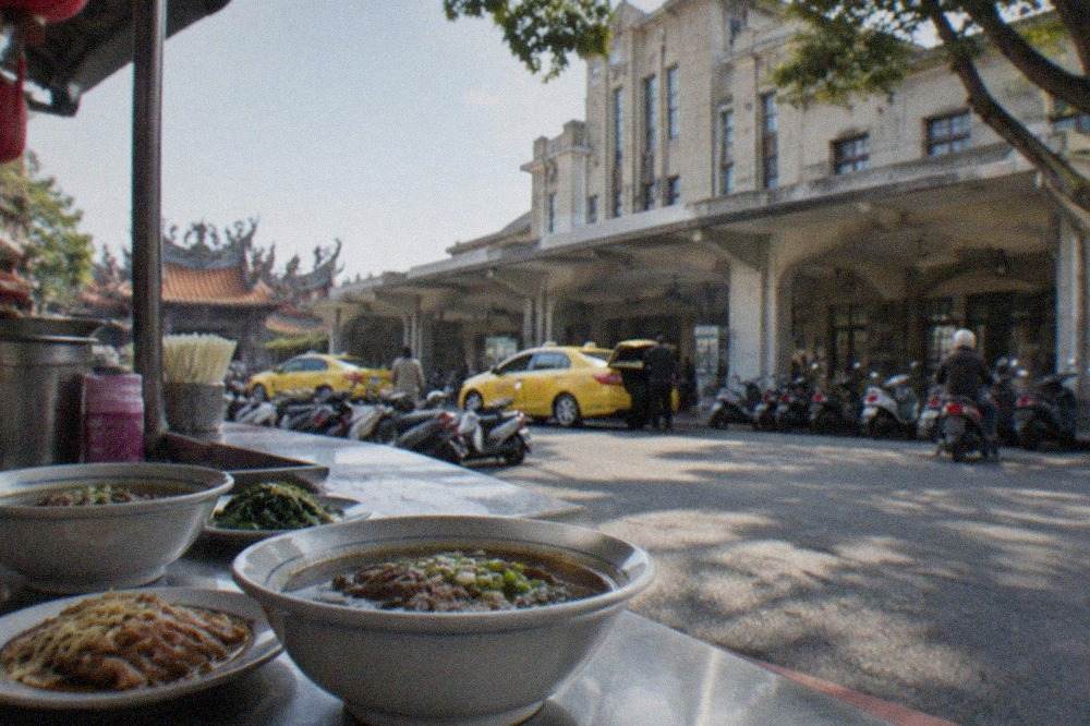 Bowls of Tainan beef soup and small plates on a street food stall counter
