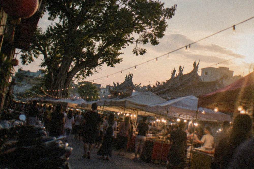Night market stalls lit up at dusk with crowds walking between food vendors