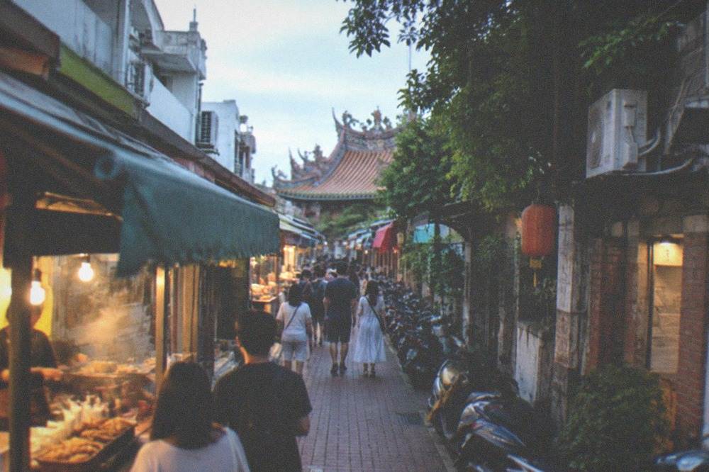Visitors walking past snack stalls along the narrow lane of Anping Old Street in daylight