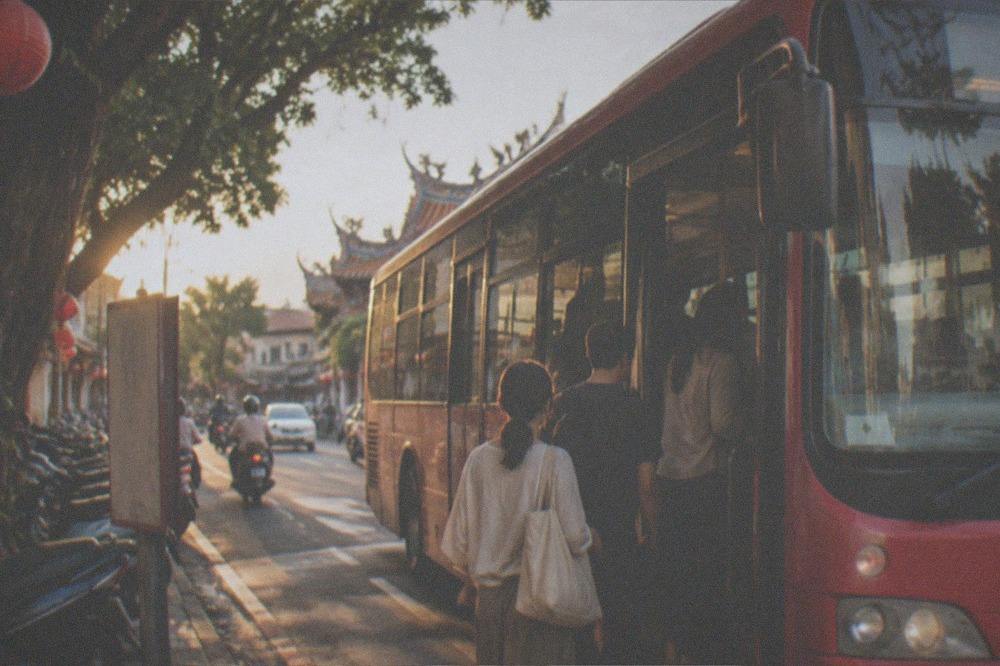 A red Tainan city bus stopped at a roadside stop with passengers boarding