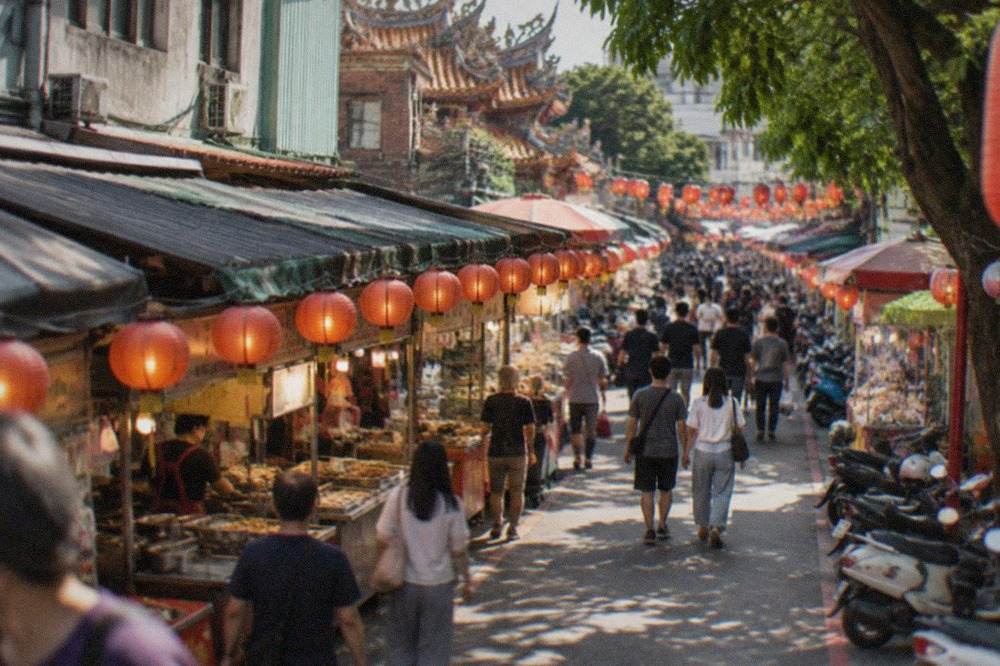 A busy night market lane in Tainan lit by rows of stall lanterns