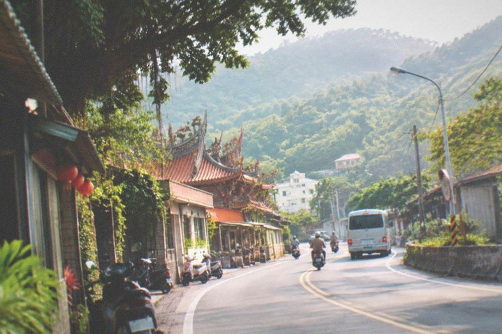 A rural Taiwanese road curving between green hills and farmland
