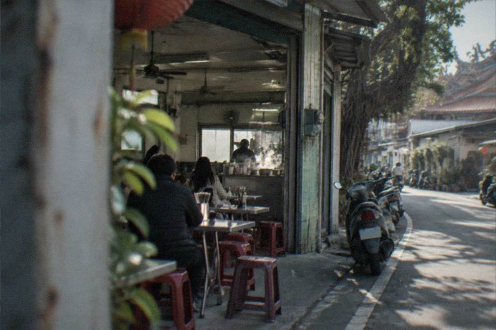 A simple rural Taiwanese eatery with open doors and plastic stools beside a country road