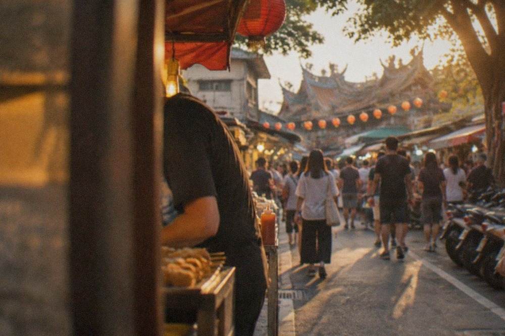 Evening crowds walking between food stalls at a large open-air night market in Tainan
