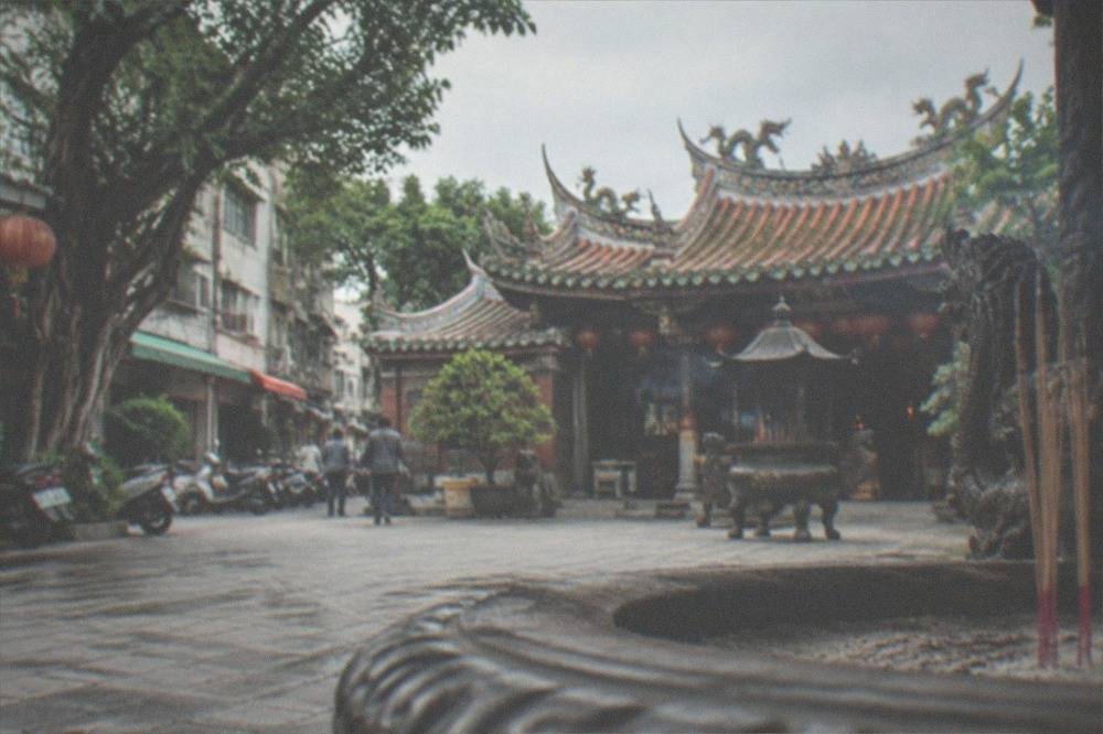 A historic Buddhist temple courtyard with tiled roofs, incense and stone paving in Tainan