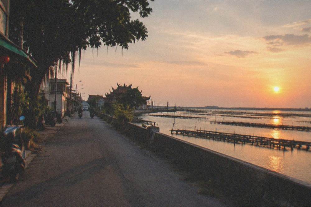 Sunset light over a wide coastal lagoon with oyster racks silhouetted on the water