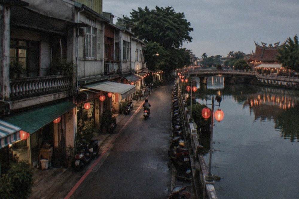 Lanterns reflected in the water of a historic harbor town at dusk