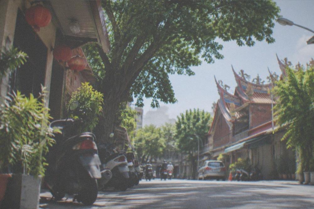 A sunny Taiwanese street with heat shimmer over the pavement and parked scooters in the shade