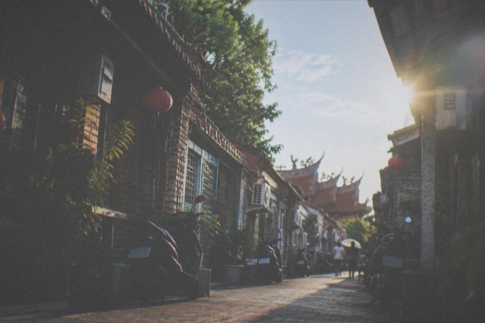 A sunny afternoon on an old street with deep shadows cast by tiled roofs