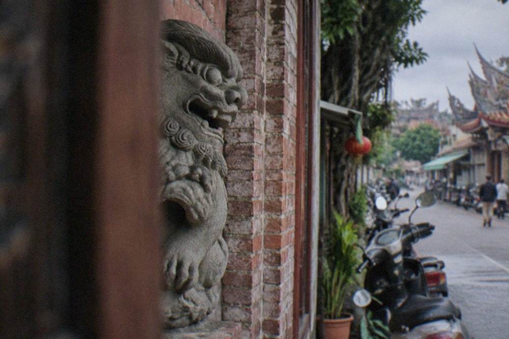 A carved stone sword lion set into the wall of an old brick building in Anping, Tainan