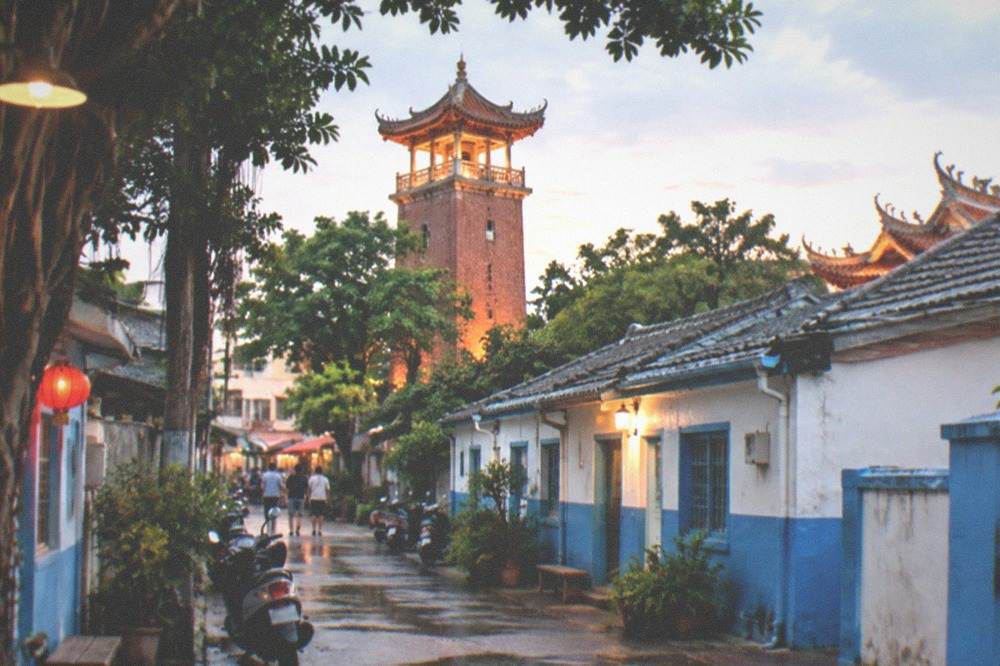 A historic red-brick tower with Chinese pavilions lit warmly against an evening sky