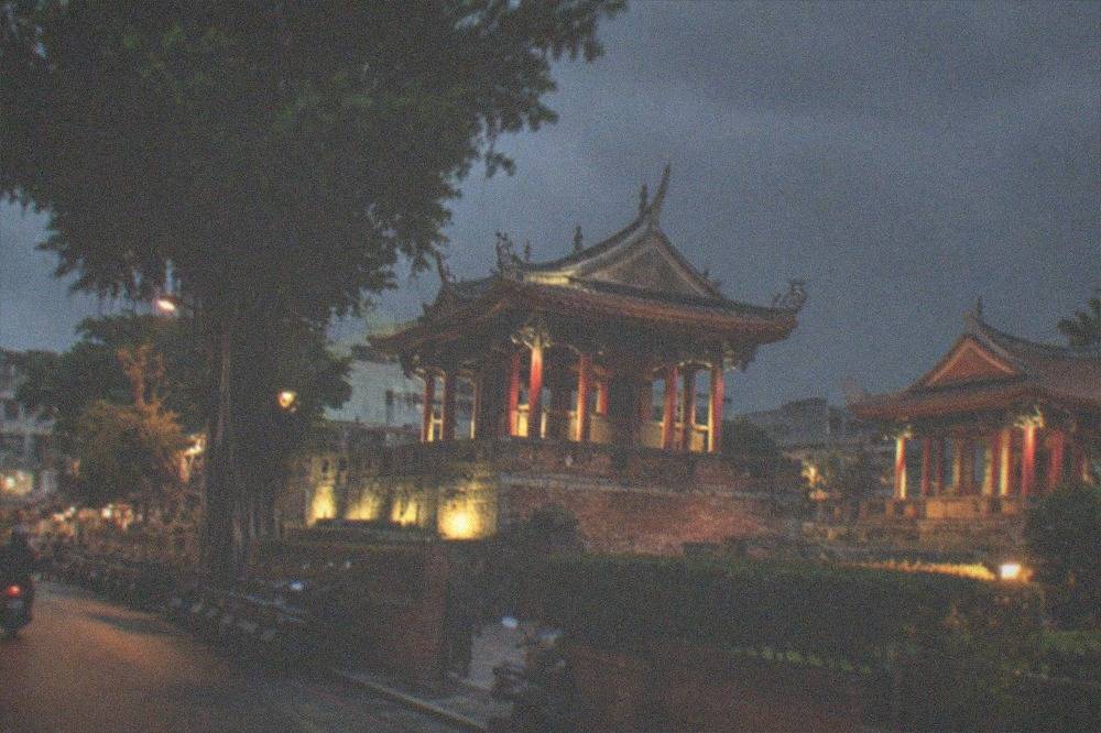 The tower and pavilions lit by floodlights against a dark evening sky