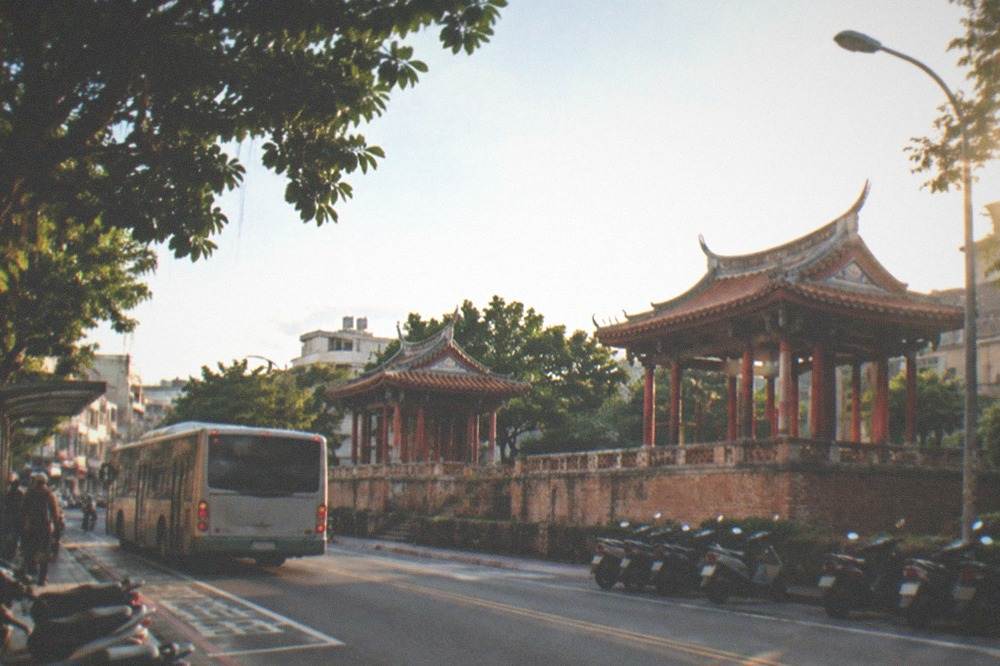 A city bus stopping at a marked stop on a street lined with scooters