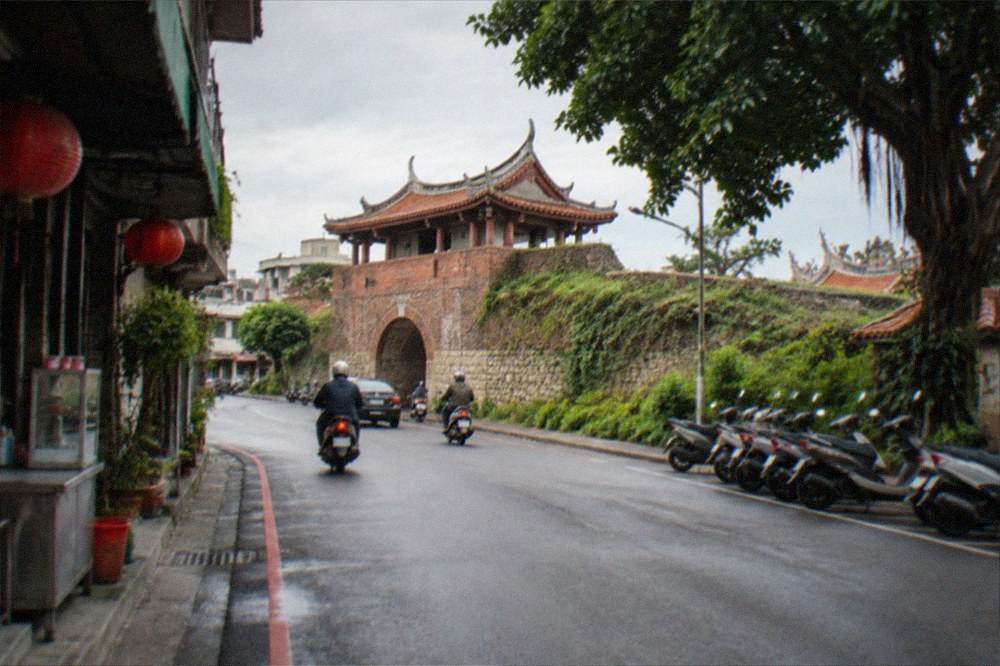 A woman in a qipao dress posing on an old street with brick facades