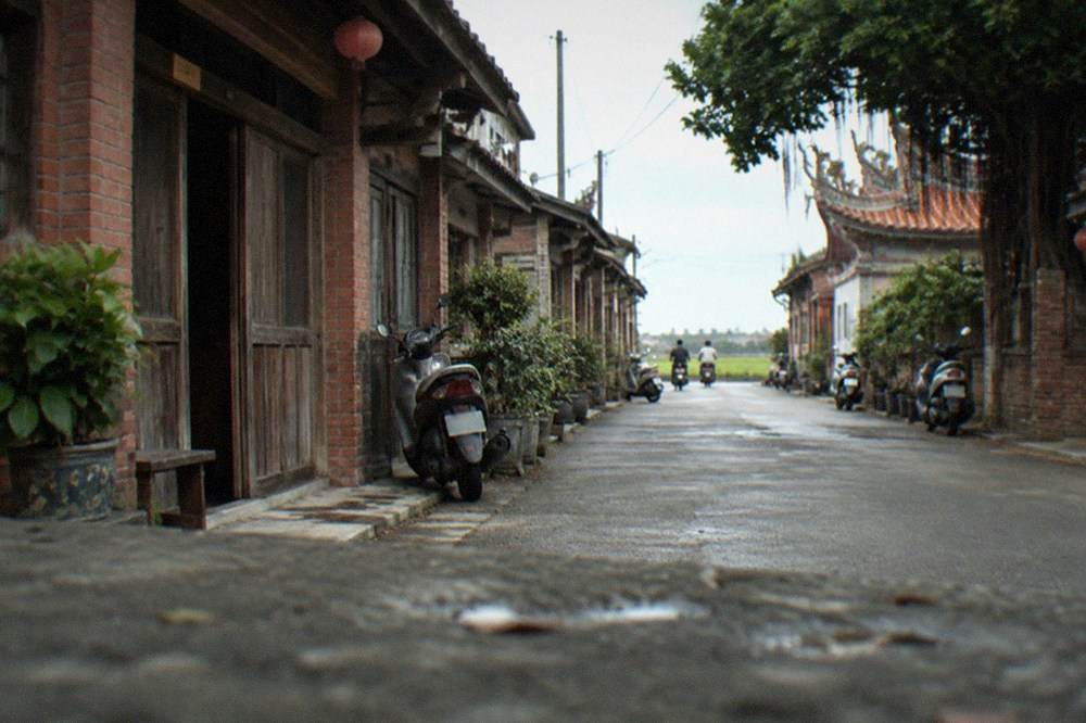 Old brick shopfronts with wooden doors standing along a narrow village street