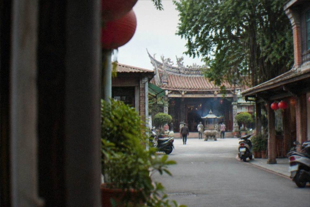 A temple courtyard with incense and carved wooden doors open to visitors