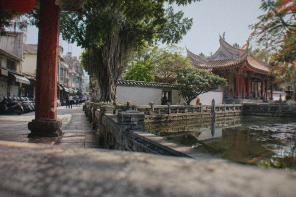 A historic shrine courtyard in Tainan with red pillars, stone paving and a tiled temple roof under a clear sky