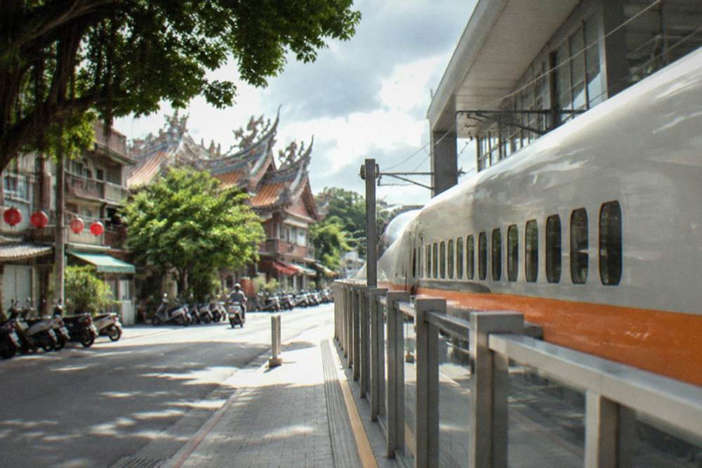 A high speed rail train stopped at a station platform beside a modern station building