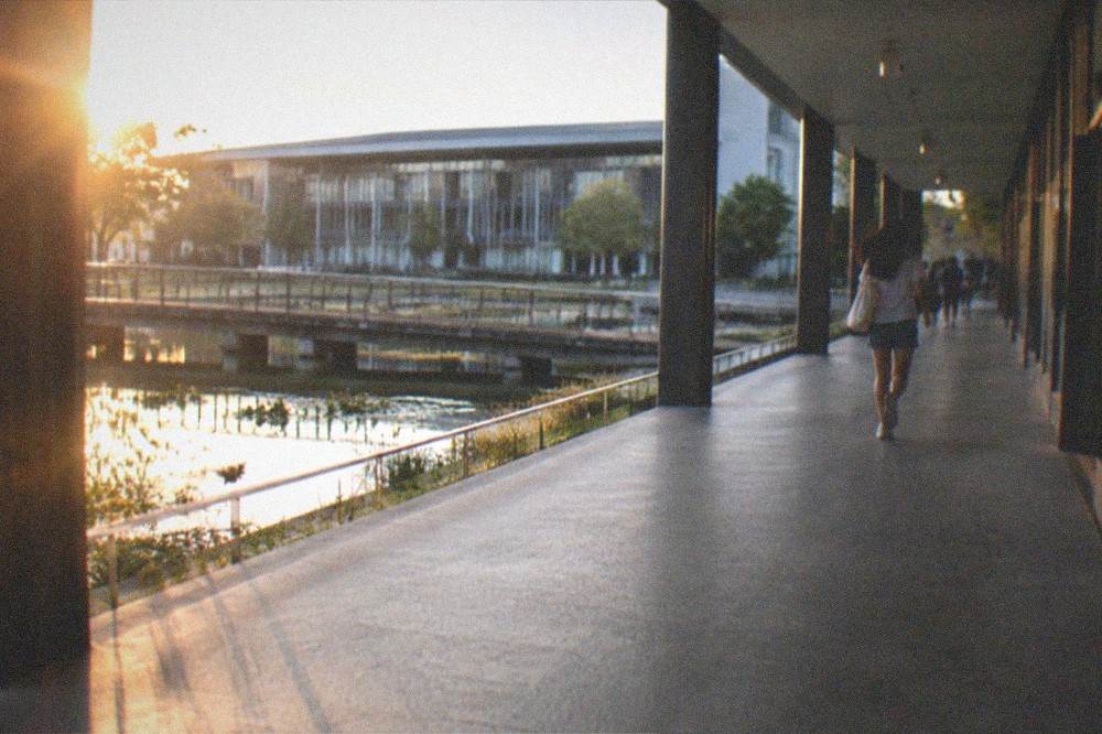 A museum corridor with photographic exhibits and visitors walking slowly past the displays