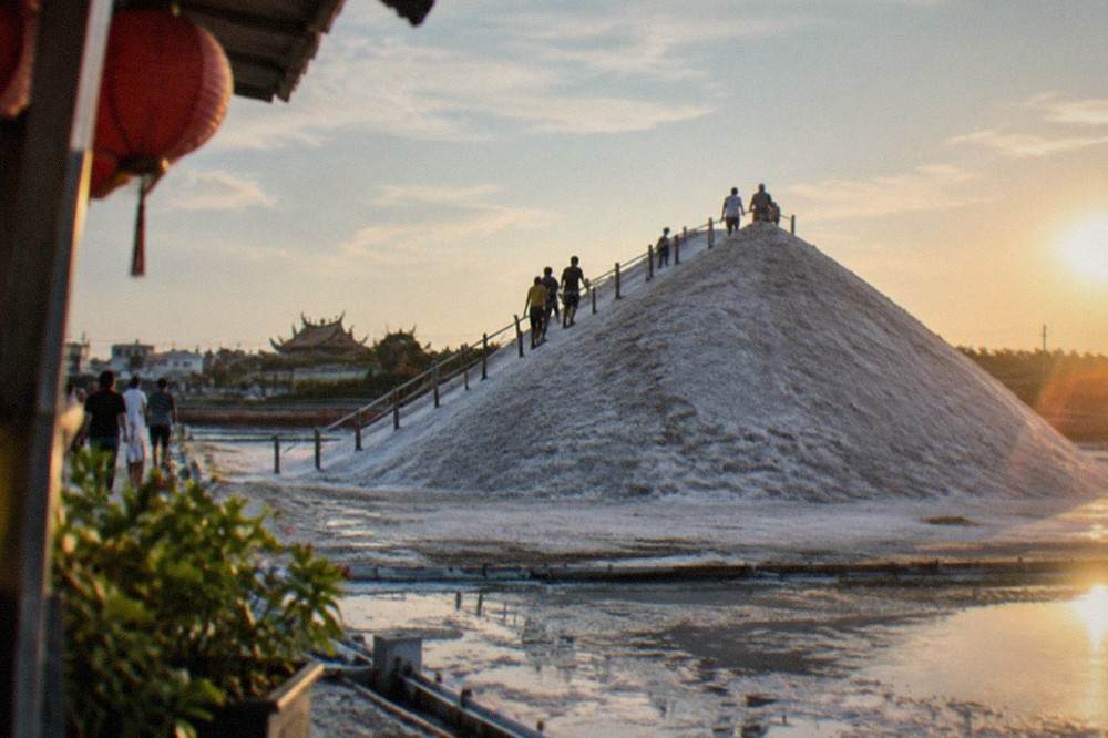 Visitors walking up a white slope of packed salt with a railing along the path