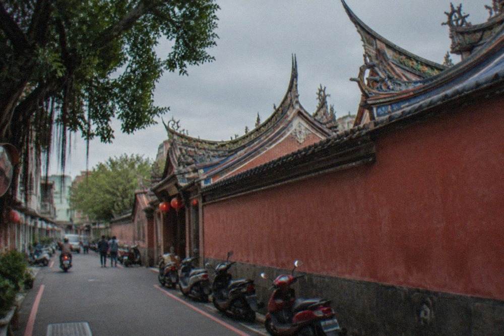 A historic Taiwanese temple courtyard with red walls and ornate roof decoration in Tainan