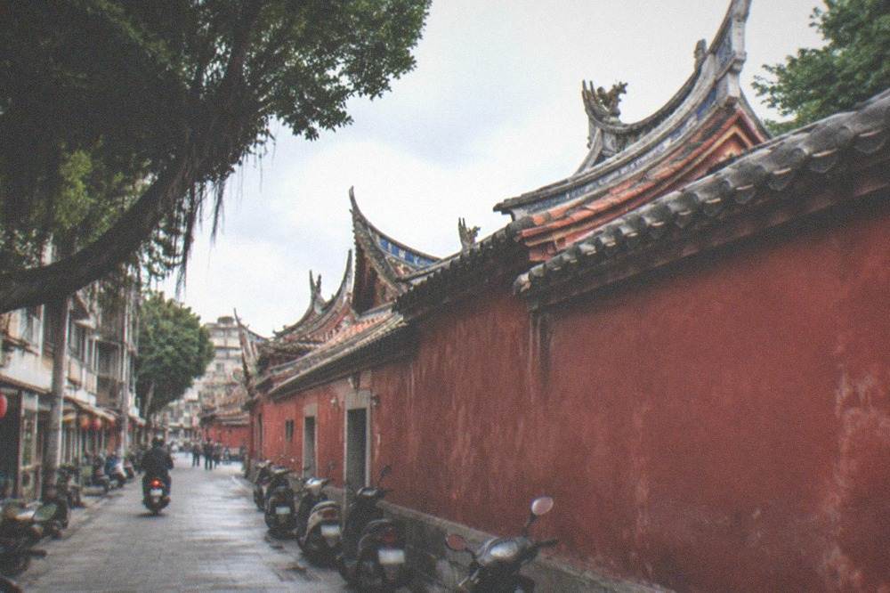 Stone courtyard paving and red temple wall under a tiled eave