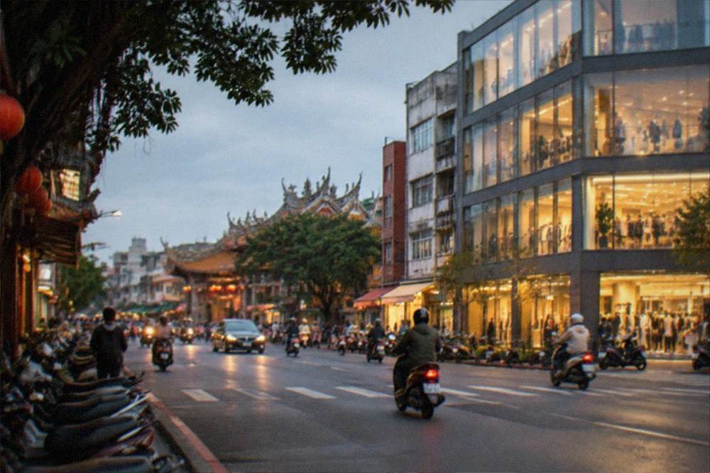 A city street in warm evening light with lit shopfronts