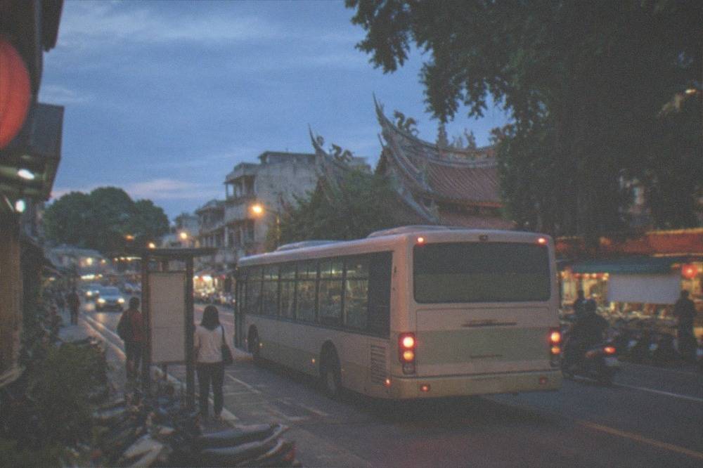 A city bus at a stop on a Tainan street in the evening