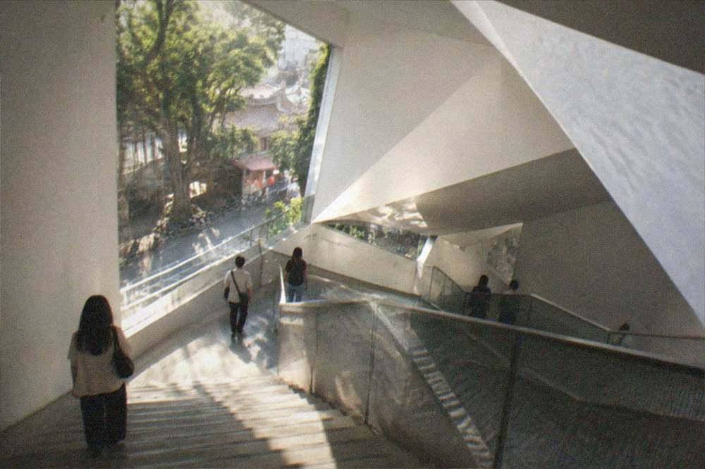 A museum staircase and landing seen from above with visitors on different floors