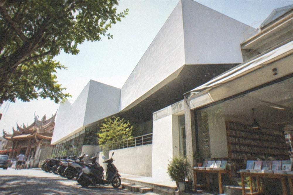 A museum gift shop and cafe area with art books on shelves and tables by a window