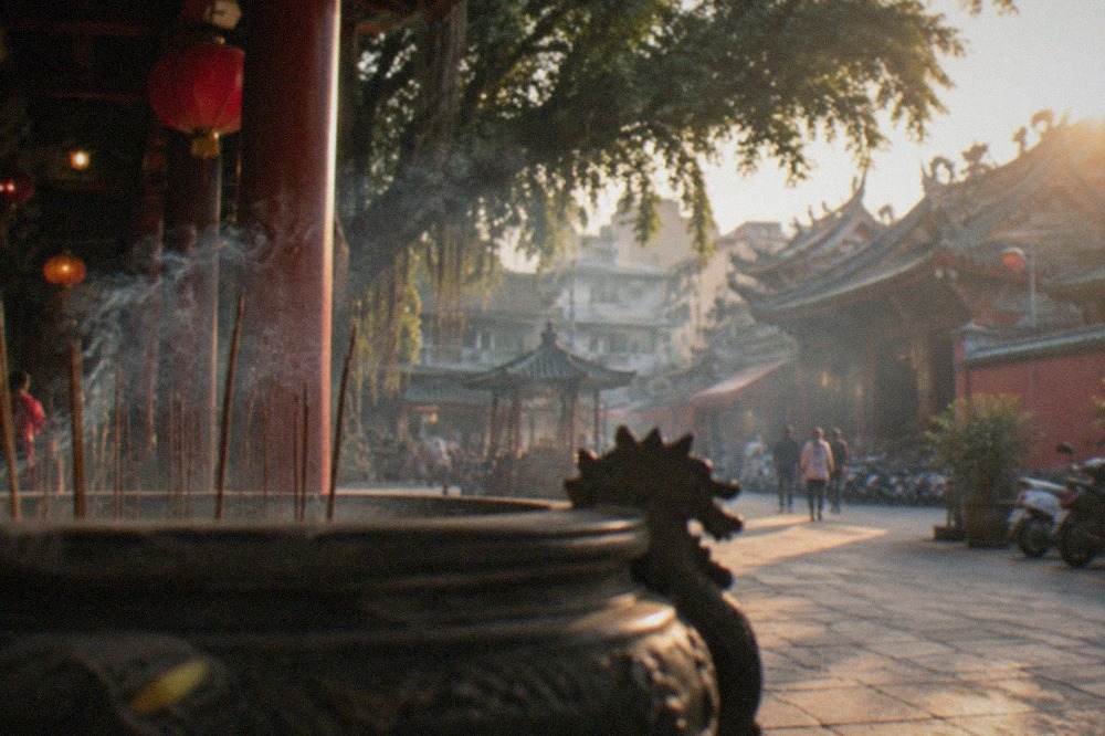 Historic temple courtyard in Tainan with red walls, stone paving and incense smoke drifting in warm evening light
