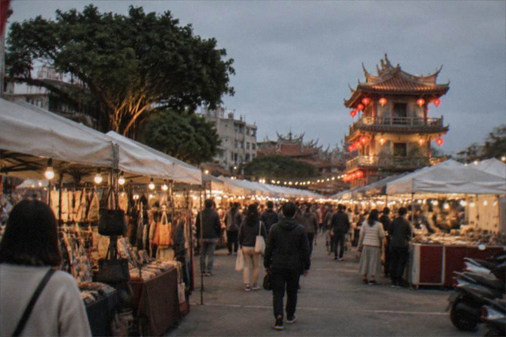 An illuminated historic tower with red lanterns seen after dark