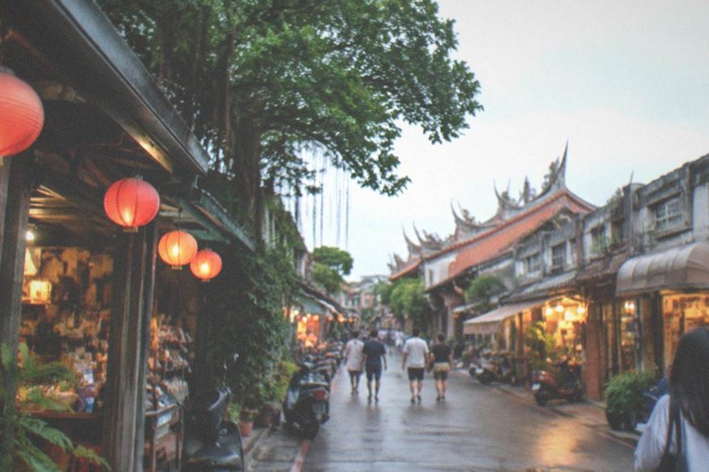 Visitors walking past illuminated old shopfronts on a narrow Tainan street