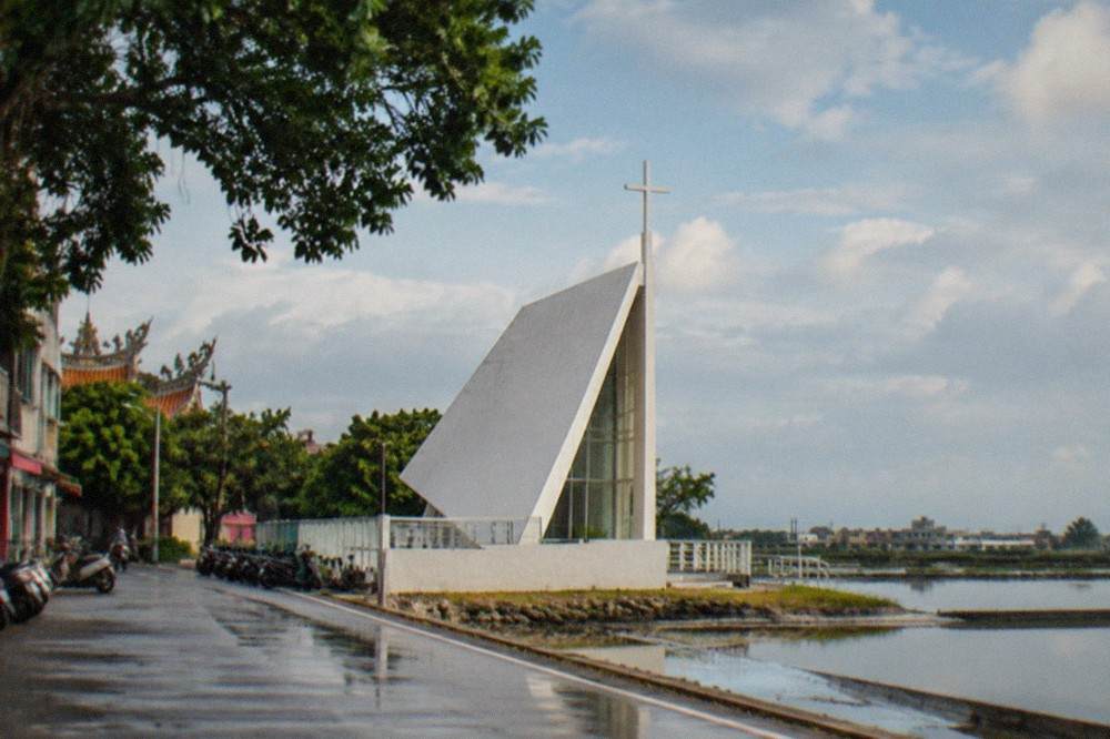 Close view of the angular white chapel structure against a wide open sky over the salt pans
