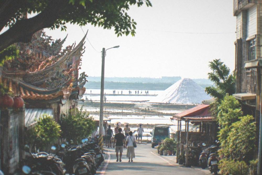 White mound of salt rising above flat coastal terrain with visitors walking on paths
