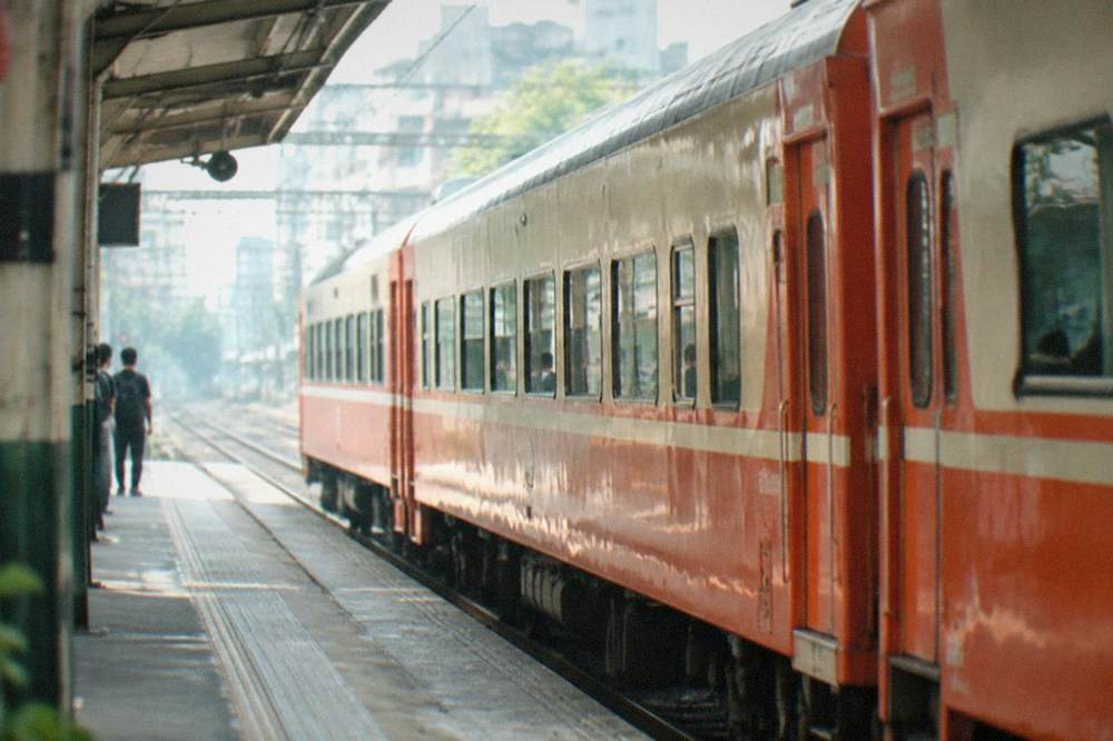 A red and orange Taiwanese intercity train at a city railway station platform