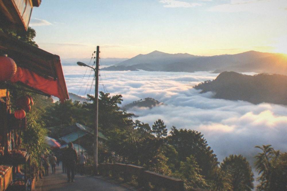 Sunrise light over a sea of clouds filling a mountain valley with forested ridges above