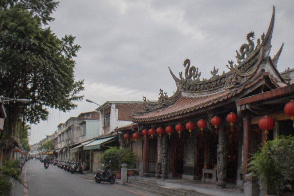 A gabled temple facade in Taiwan with carved wooden eaves and red lanterns hanging along the front
