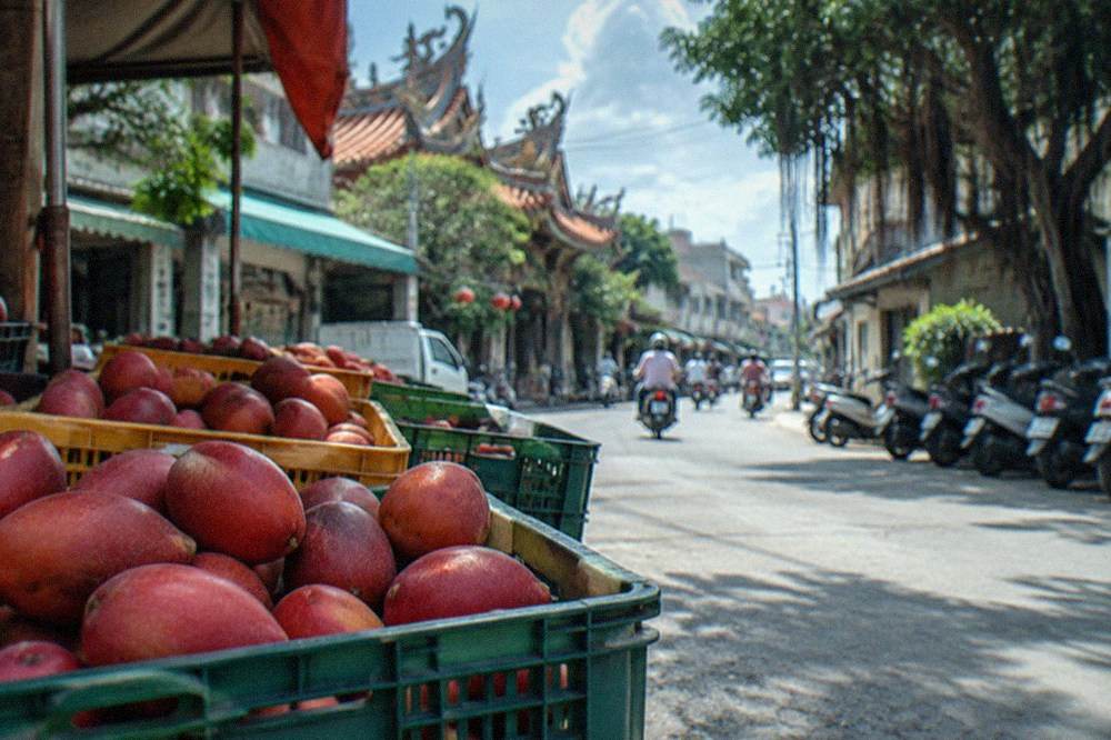 Crates of fresh red Irwin mangoes stacked at a roadside stall in summer