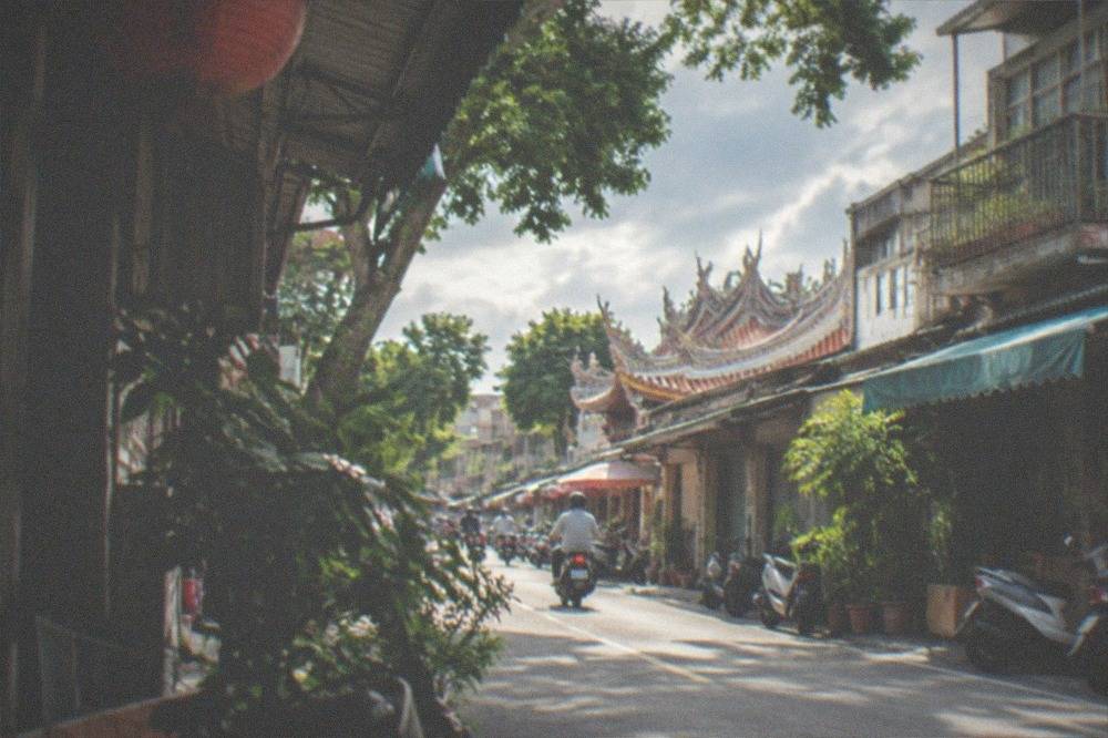 A city street in central Tainan with scooters and old shopfronts in the late afternoon