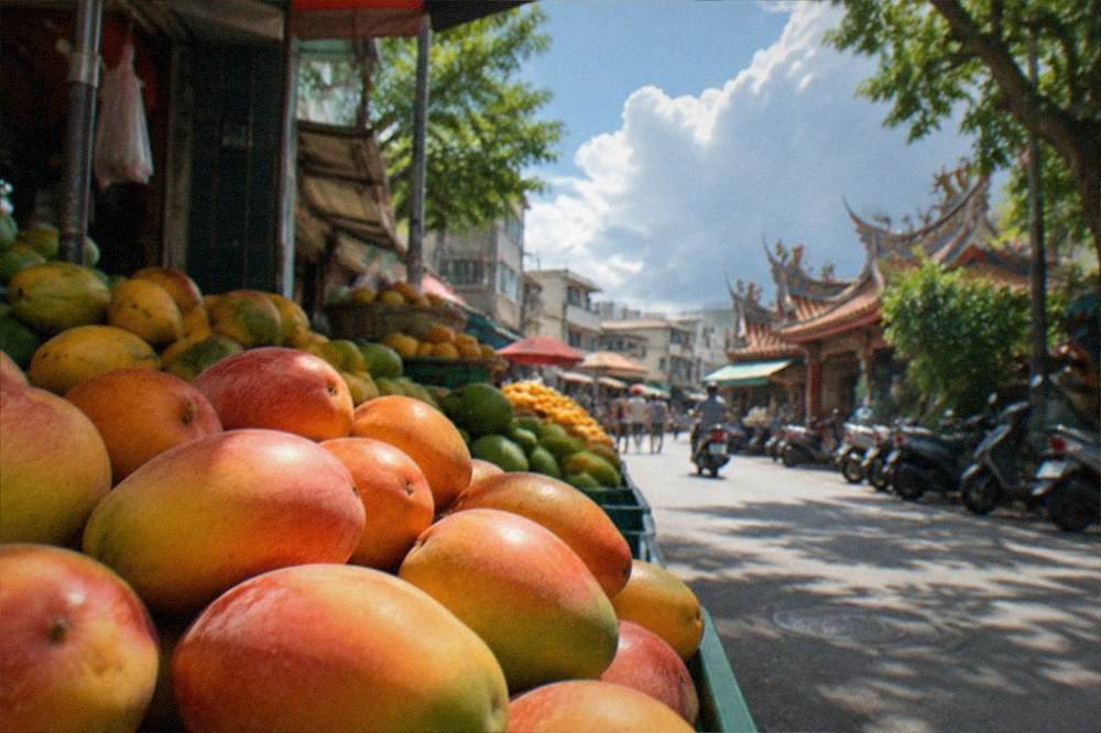 Fresh mangoes stacked at a fruit stall in a Tainan market during summer