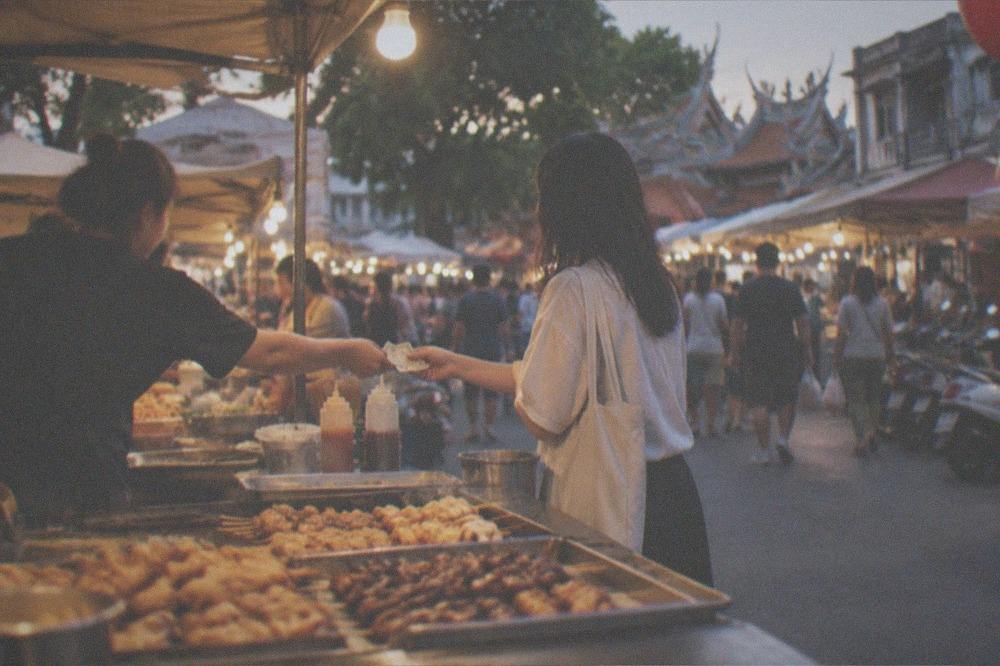 A night market stall in Tainan with a customer paying cash for street food