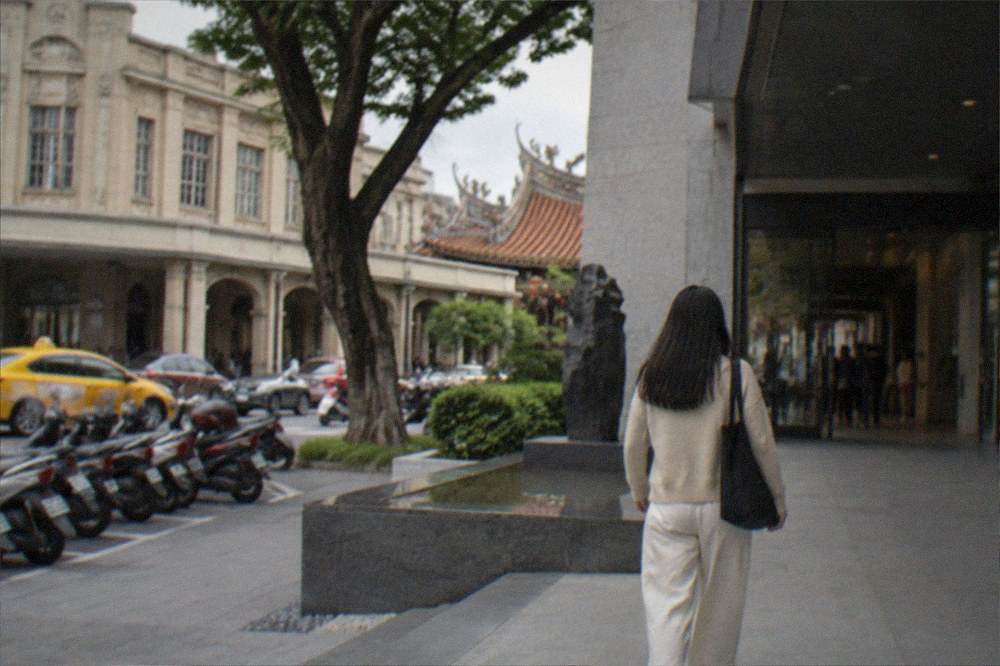 A visitor walking toward the entrance of a modern museum building in Tainan