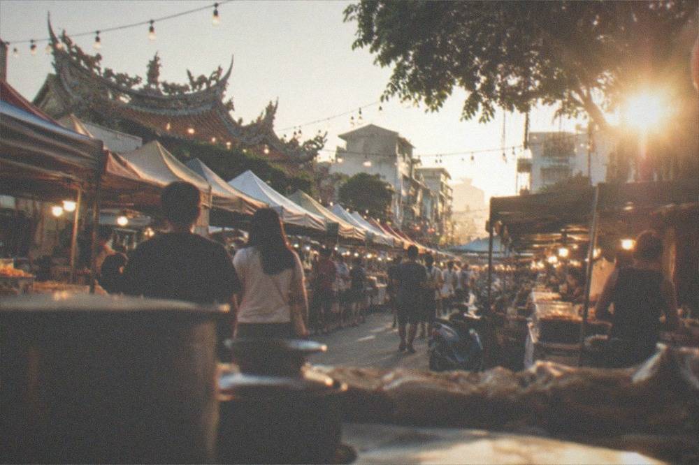 An indoor night market aisle with food stalls under a covered roof