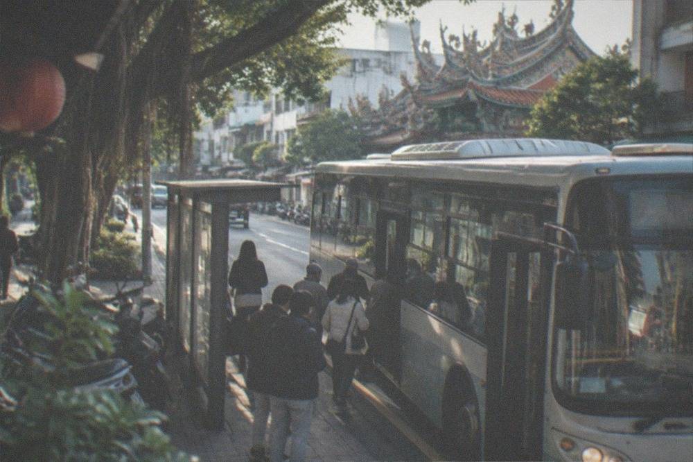 A city bus at a stop on a Tainan street with passengers boarding