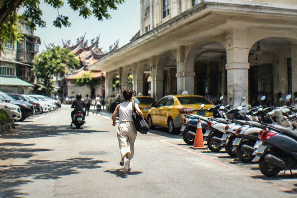 Cars parked in tight rows in a small private parking lot between older buildings