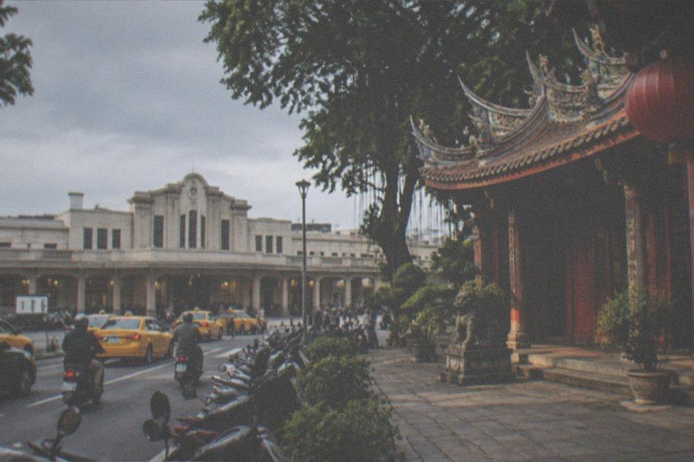 A historic Tainan temple courtyard with stone paving and red wooden doors in warm afternoon light